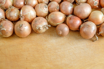 Yellow onions lie on top of a wooden table.