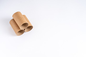 Three toilet paper bushes lie in the shape of a pyramid on the left on a white table.
