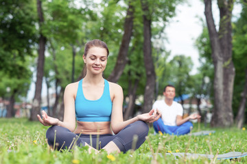 Girl meditates in lotus pose on green grass