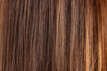 Glossy brown hair texture, background. Close view of long straight women's hair. Hair care concept.