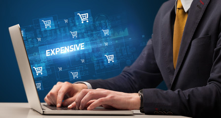 Businessman working on laptop with EXPENSIVE inscription, online shopping concept