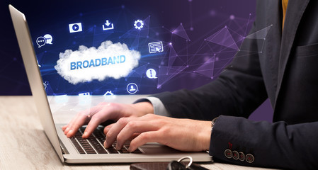 Businessman working on laptop with BROADBAND inscription, modern technology concept