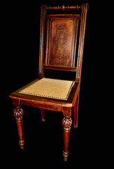 Old handmade chair with chiseled legs on a black background