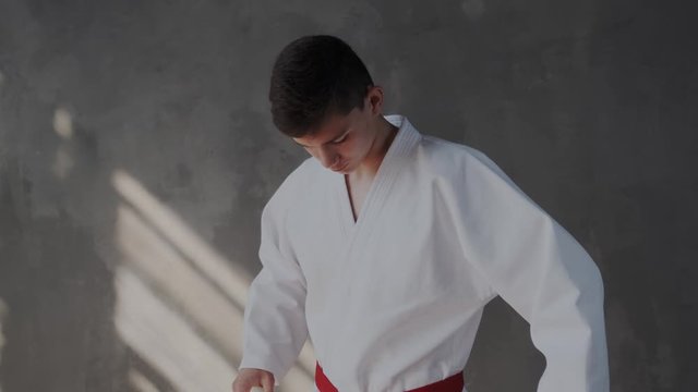 The generous young fighter in kimono is focused and ready for battle. He looks directly at the camera as she approaches a close-up. Taekwondo traditional martial arts.