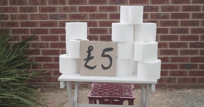 Children have a toilet paper stand outside of their house in the UK selling rolls of toilet paper taking advantage of a toilet paper shortage. There is a hand painted sign with 5 pounds written on it
