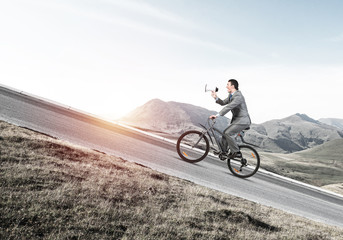 Businessman with megaphone in hand on bike
