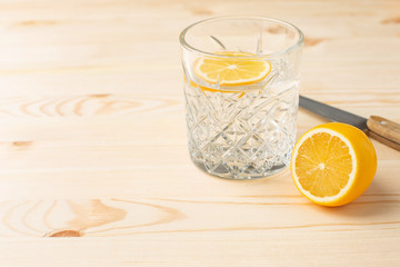 Glass of water with lemon on a wooden table with copyspace, morning drink for a healthy lifestyle