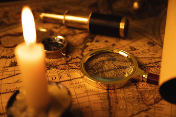 exploration - collection of antique objects on old world map in candlelight