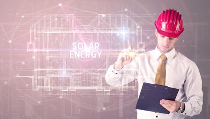 Handsome architect with helmet drawing SOLAR ENERGY inscription, new technology concept