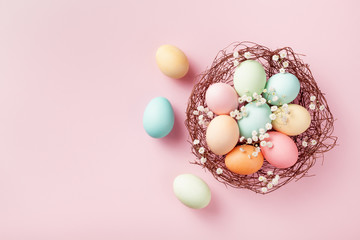 Fototapeta na wymiar Pastel Easter eggs in nest on pink background top view. Flat lay style.