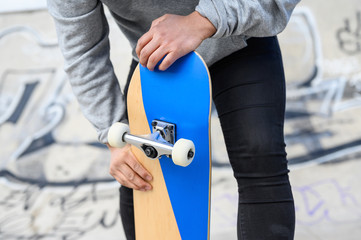 Close up of unrecognizable young man holding longboard or skateboard in the park .