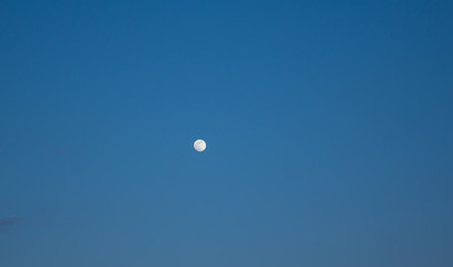 Rising moon in the light blue evening sky