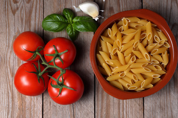 Ingredienti crudi da usare per la preparazione di un gustoso piatto di penne rigate con pomodoro aglio e basilico. Piatto tipico della cucina italiana.