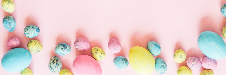 Stylish background with colorful easter eggs isolated on pink pastel background with blooming...