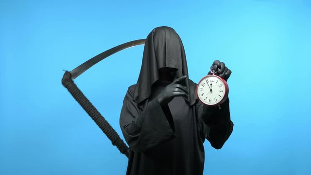 A man in a death suit with a scythe, shows a clock. blue background