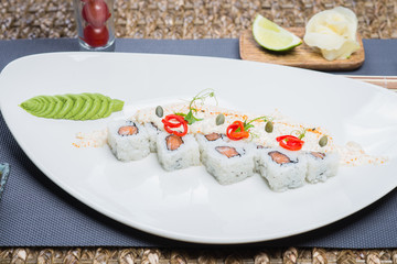 Traditional rolls with fish and rice on a white plate with sauce and wasabi. Japanese food.