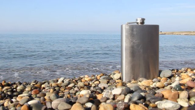 vintage metal hip flask on pebbles on a beach. celebration of men's holiday at sea. conception International Men's Day and Fatherland defender day February 23. copy space