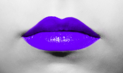 Female lips close-up with purple ultraviolet lipstick bright juicy color on a background of black and white face.