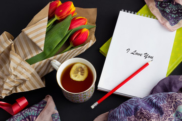 Notepad, pencil and tulips on a gray background