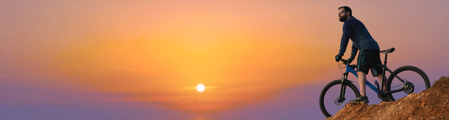 Conquering mountain peaks by cyclist in shorts and jersey on a modern carbon hardtail bike with an air suspension fork . Beautiful view from the mountain. Panoramic view for banner.