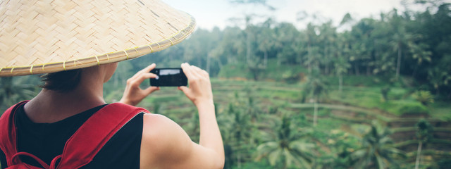 Fototapeta premium Young woman tourist taking picture using her smartphone camera in beautiful green jungles. Wide screen