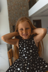 Little girl with red hair shows different emotions. Sadness, joy and happiness. She smiles and cries. In a black dress with skin pigment on her face, freckles