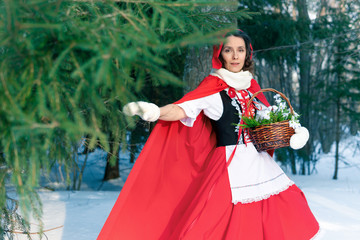 Girl in a red dress and hat walks through a snowy winter Park