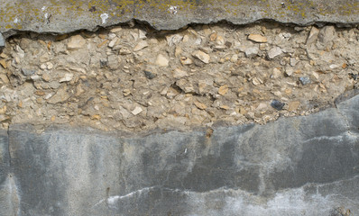 Background from old crumbling concrete. A piece of plaster fell off and the stones stick out of...