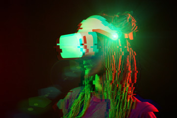 Woman is using virtual reality headset. Neon light studio portrait. Image with glitch effect.