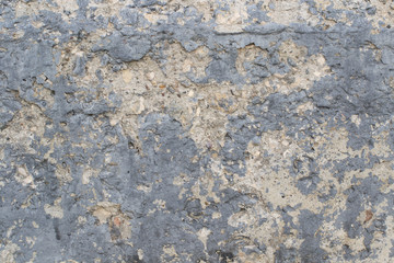 Background from old crumbling concrete covered in black paint. Stones stick out of old cement. Close-up. High quality