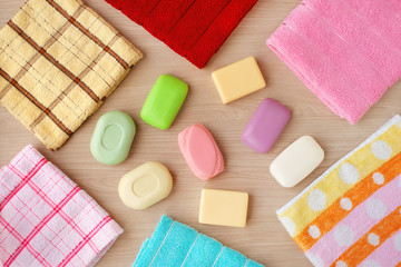 Obraz na płótnie Canvas Multi-colored soap and bath towels. Solid soap of different colors and shapes on a wooden background. Bath towels are folded in the shape of a frame. Hygiene products create a backdrop.
