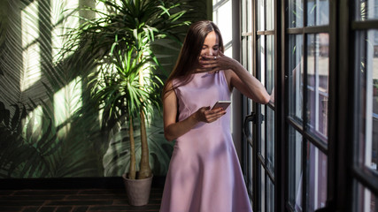 Beautiful young woman near a huge window.