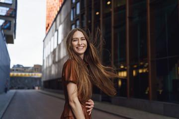 Waist-up outdoor portrait of charismatic gorgeous woman having fun, feeling happy, laughing as turn...