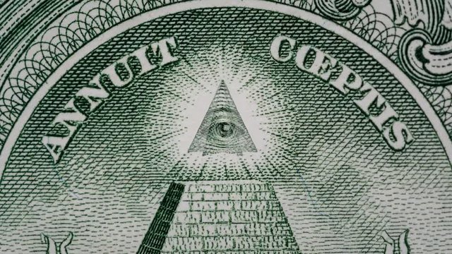 Creative 4k parallax video of details of 1 American dollar banknote with a rotating eye at the top of the pyramid. Macro view.