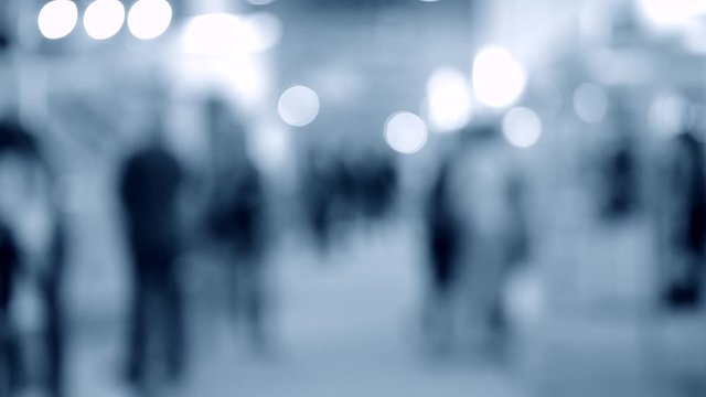 Many people walk inside the mall exhibition store. Blurred Background
