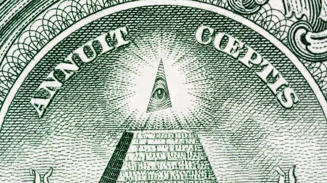 Creative 4k parallax video of details of 1 American dollar banknote with a rotating eye at the top of the pyramid. Macro view.