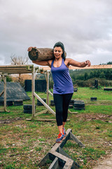 Female participant in an obstacle course carrying trunks outdoors