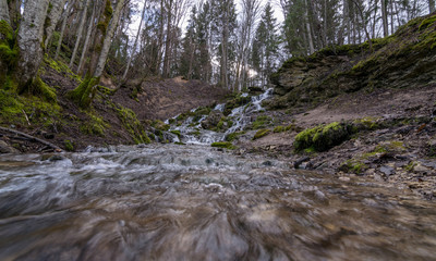 A stream of water flowing over rocks and creating a waterfall effect.