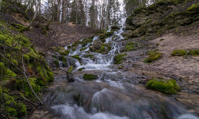 A stream of water flowing over rocks and creating a waterfall effect.