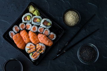 A top down view of a variety of sushi with soya sauce and sesame seeds ready for eating.