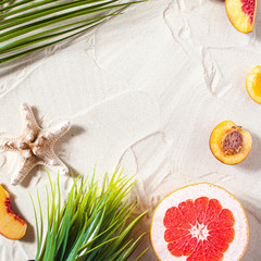 Beach vacation. A palm leaf, starfish, and white tree branch and juicy fruits lie on white fine...