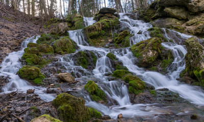 A stream of water flowing over rocks and creating a waterfall effect.