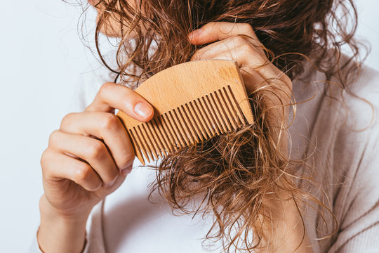 Young woman combing tangled ends of her curly hair