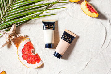 Safe sun. Skin care. A tube of cream lies on the beach sand, surrounded by vibrant fruits, corals,...