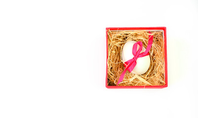 Easter celebration. White easter egg tied with a red ribbon lies in a red gift box isolated on a white background. Easter background