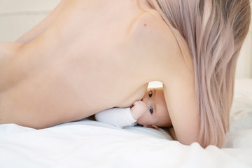 Woman breastfeeding newborn baby. Mother breastfeeding newborn boy lying in bed. Concept breast feeding. Baby eating mother's milk. Young woman nursing and feeding baby. Concept of lactation infant.