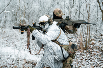 Two men in camouflage white, green uniform with machineguns back to back. Soldiers with muchinegun...