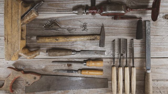 Vintage woodworking tools, hand drill, chisels, saw, plane, rasps and screws moving and leaving an opening for logo or text. Carpentry, diy, craftsmanship  and knollingconcept, flat lay 4k stop motion