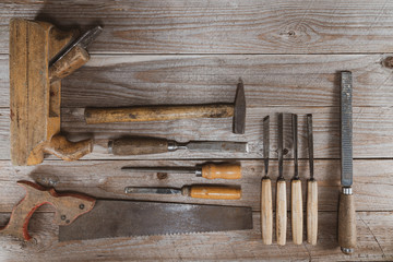 Vintage woodworking tools on a wooden background. Chisels, rasps, plane and a hand saw neatly...