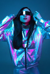 Neon portrait of a girl of Asian appearance, dressed in futuristic clothes and glasses. Neon blue and pink light. Virtual reality glasses